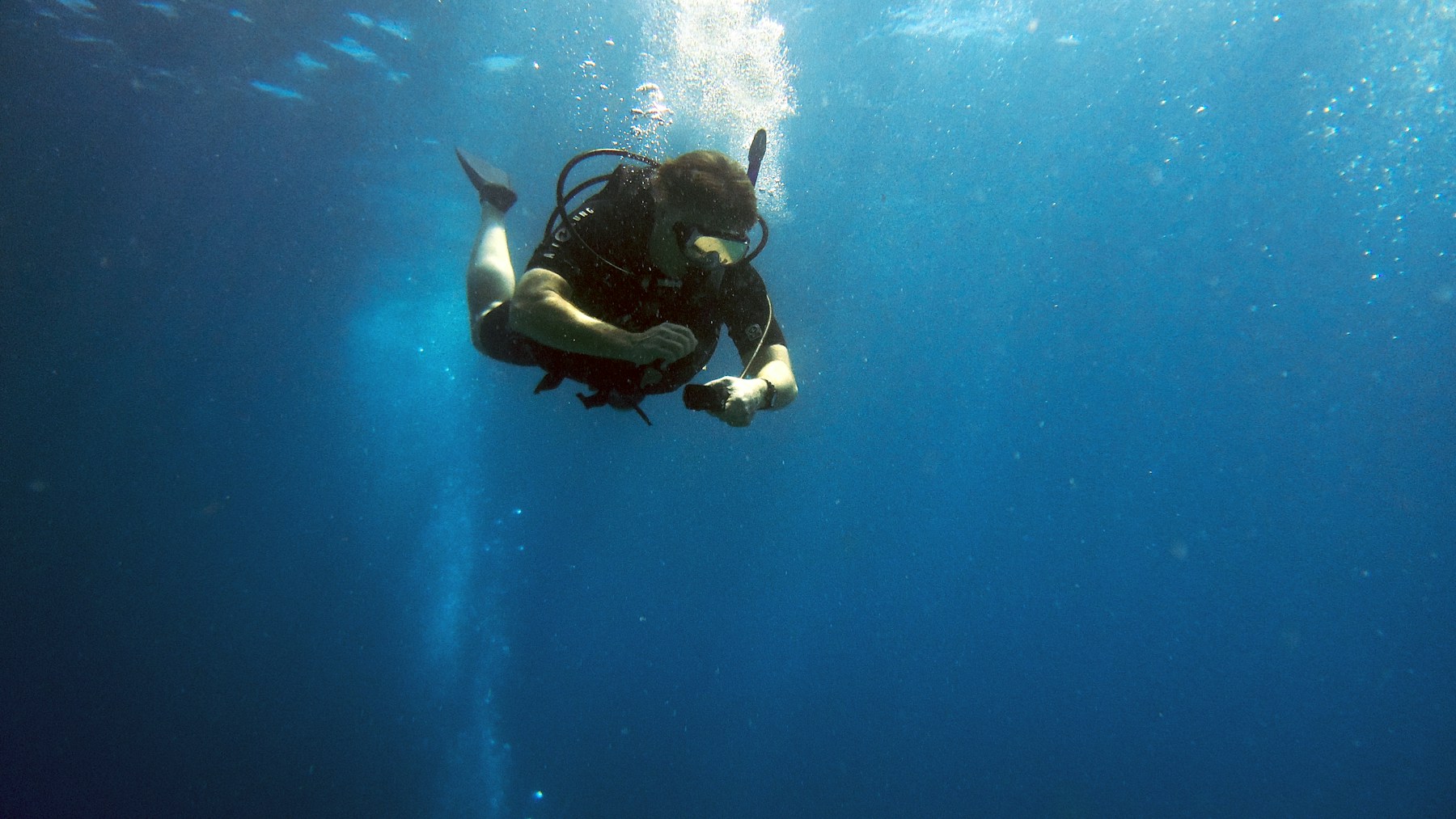 A scuba diver checking instruments while descending
